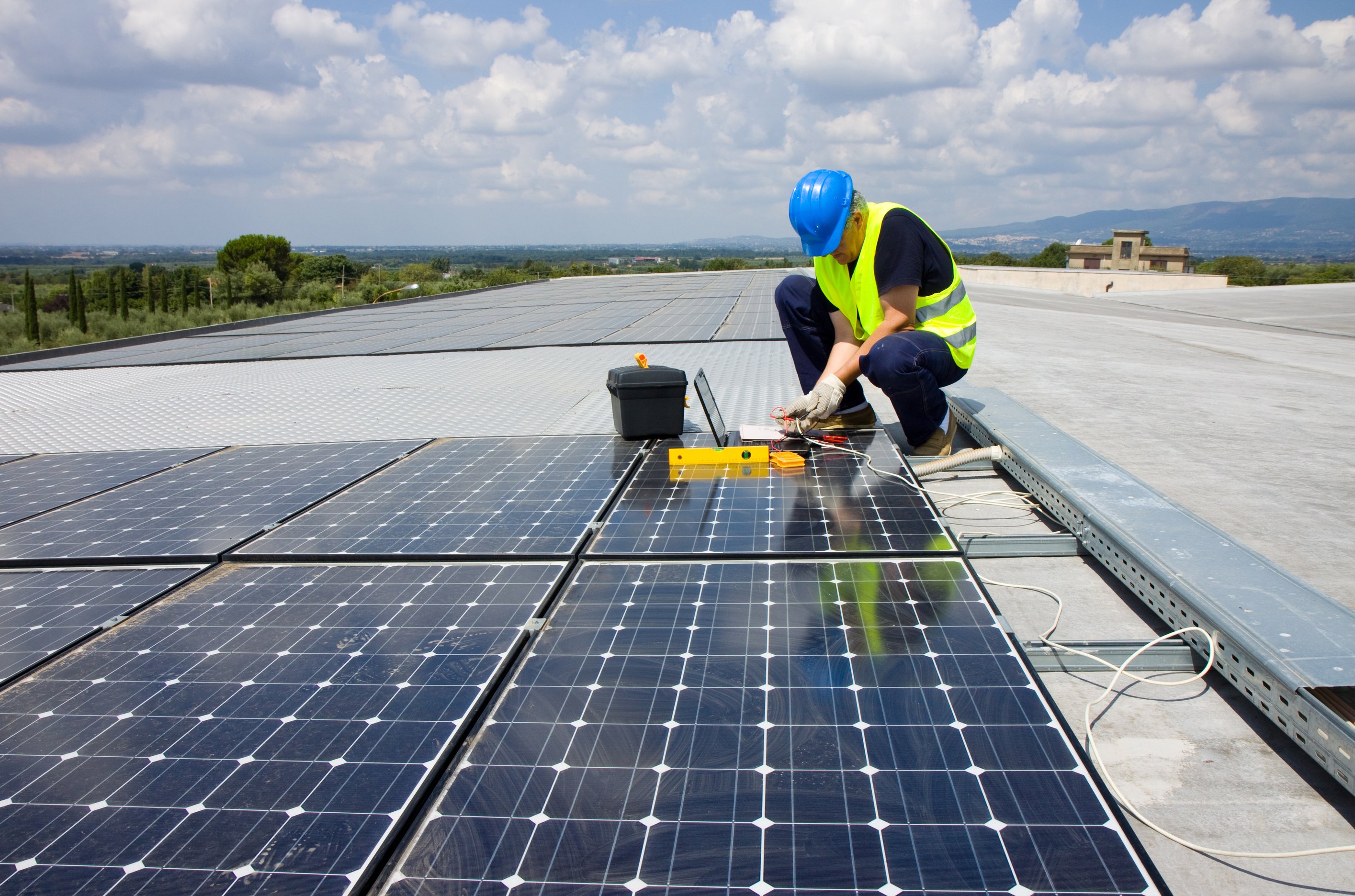 Tradesman installing solar panels on roof